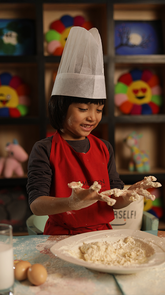 Lifestyle photography of a child chef learning cooking through a playful hands on kitchen activity