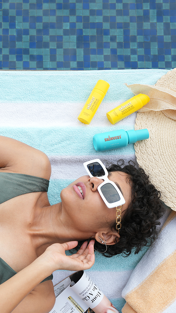 Skinvest skincare products placed beside a woman relaxing poolside with sunscreen and skincare bottles lifestyle beauty photography for summer skincare routine